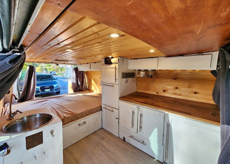 the interior of an rv with wood paneling on the walls and floor, including a bed