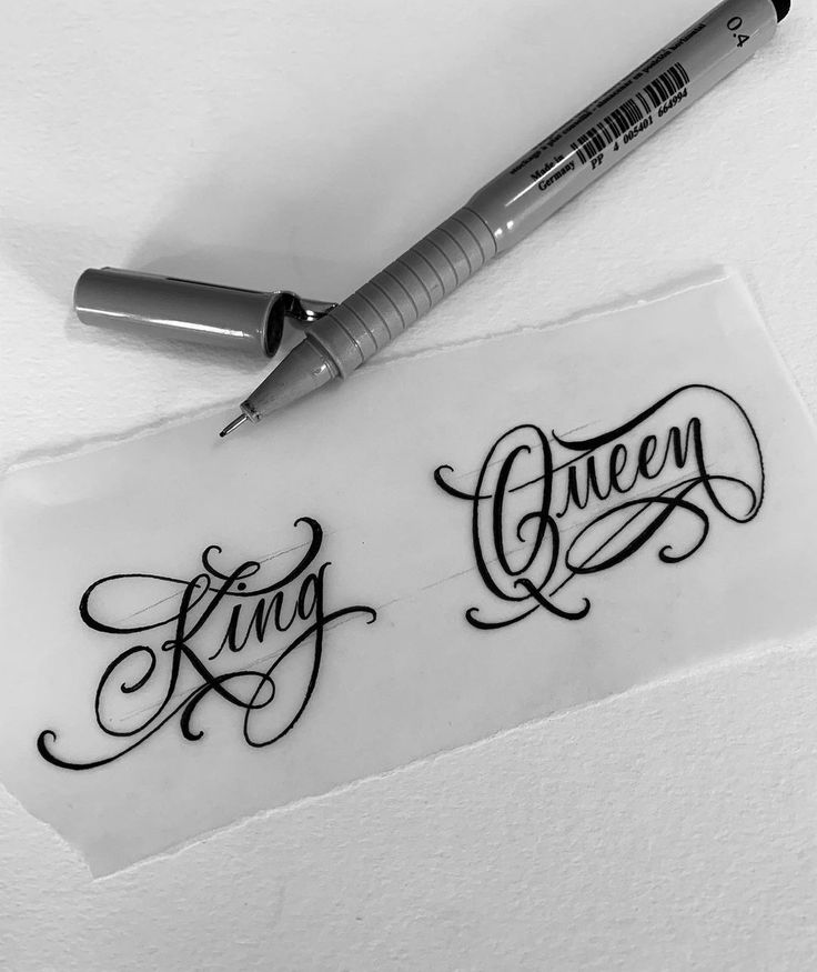 a pen sitting on top of a piece of paper with the word queen written in cursive writing