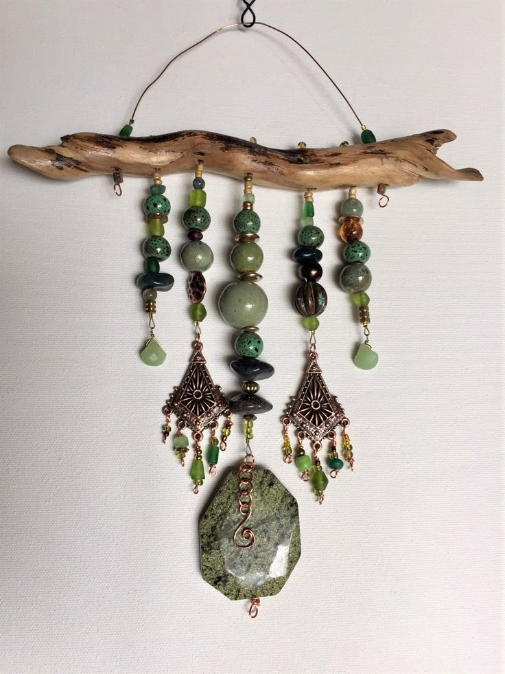 a piece of driftwood is hanging on the wall with green beads and other items