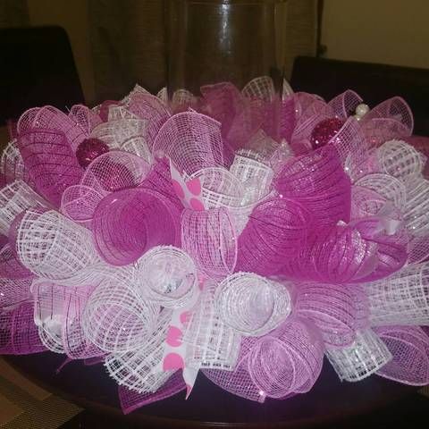 pink and white hair bows sitting on top of a black plate with a vase in the background