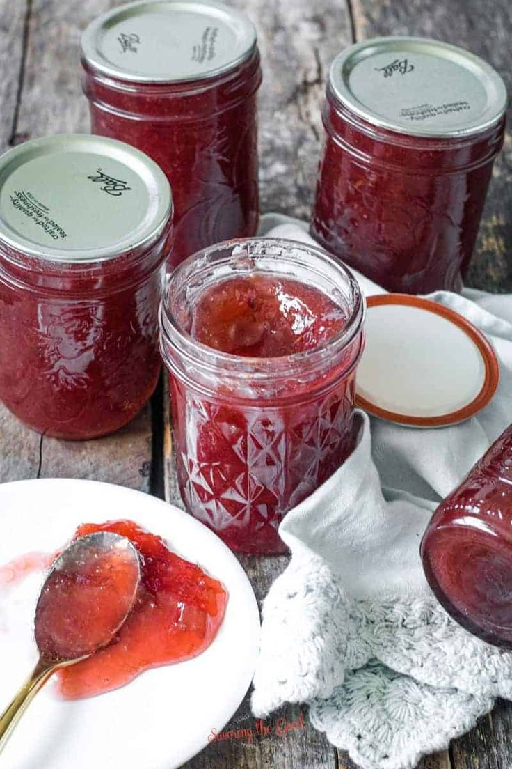 several jars filled with jam on top of a wooden table