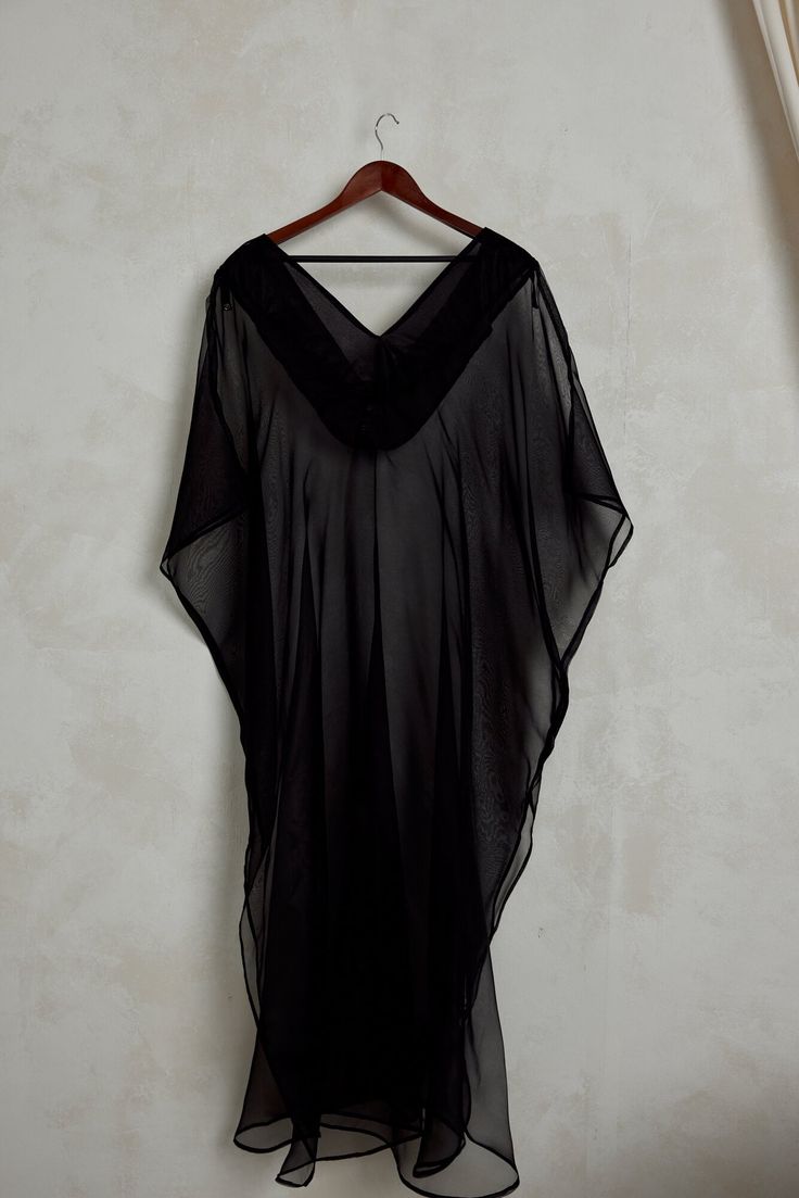 The Diana Kaftan serves sheer luxury romance and is made from 100% silk organza. Crisp and smooth with a matte finish, this black sheer kaftan can be layered over your favorite swimsuit or bodysuit. Diana is intentionally minimal to allow you to style and accessorize to your hearts desire. Elevate your lounging, evening events and resortwear with its breezy high side slits and ultimate versatility. You can style Diana with wide legged trousers or jeans for a more fun look. We recommend dressing Chic Silk Kaftan For Beach Cover-up, Elegant Silk Chiffon Beach Dress, Flowy Party Beachwear Cover-up, Sheer Flowy Cover-up, Flowy Sheer Cover-up, Elegant Silk Beach Cover-up Dress, Black Flowy V-neck Cover-up, Sheer Silk Beach Dress, Black Silk Chiffon Summer Dresses