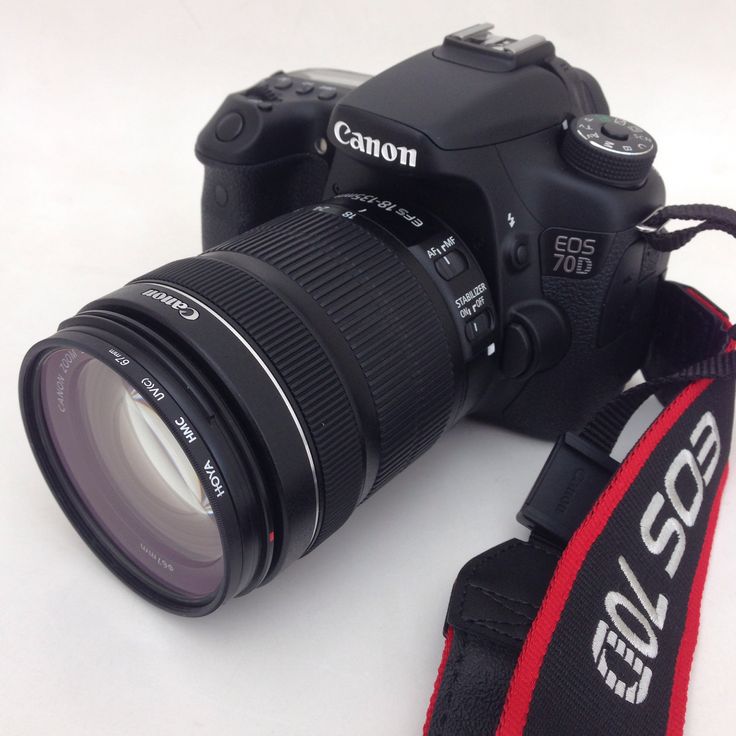 a canon camera sitting on top of a white table next to a red and black strap