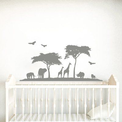 a baby crib with an elephant and giraffe wall decal