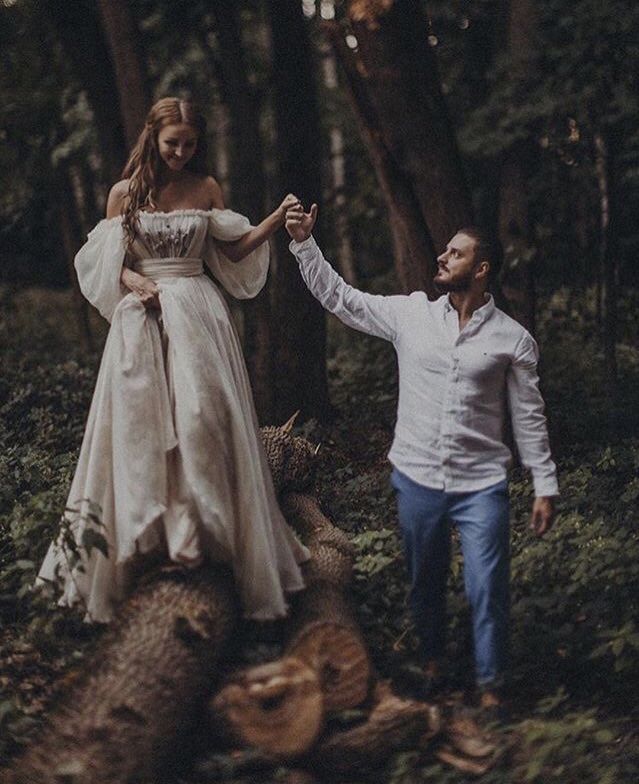 a man and woman are walking through the woods