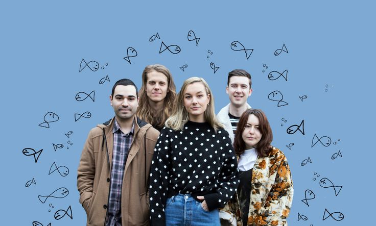 a group of people standing next to each other in front of fish drawn on the wall