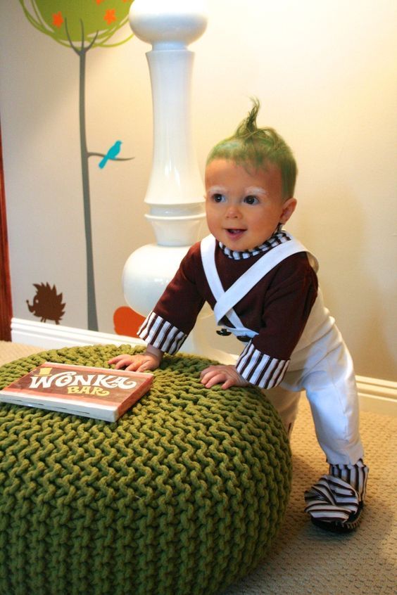 a little boy sitting on top of a green poufce ottoman in front of a lamp