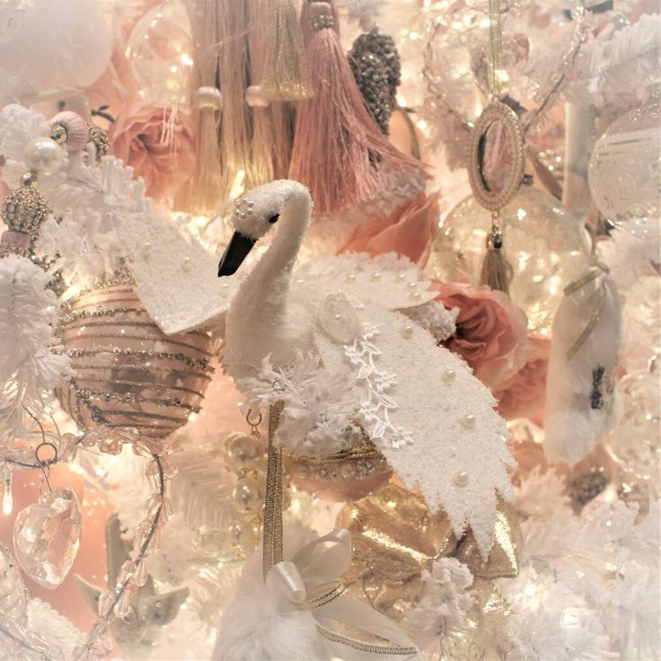 a white swan is standing in front of some christmas decorations and ornaments hanging from the ceiling