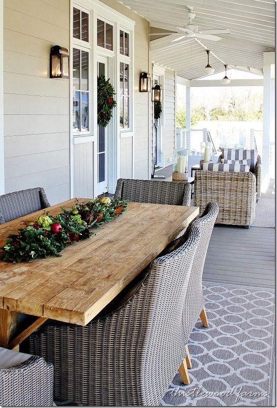 a wooden table sitting on top of a patio next to wicker chairs and windows