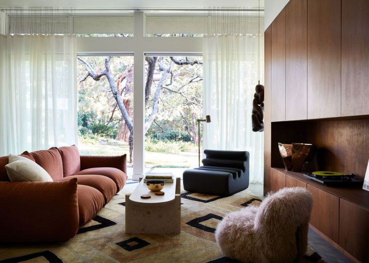 a living room filled with furniture next to a large open window covered in white curtains