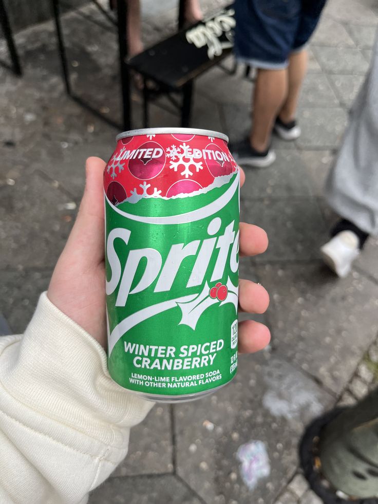 a person holding up a can of spritet