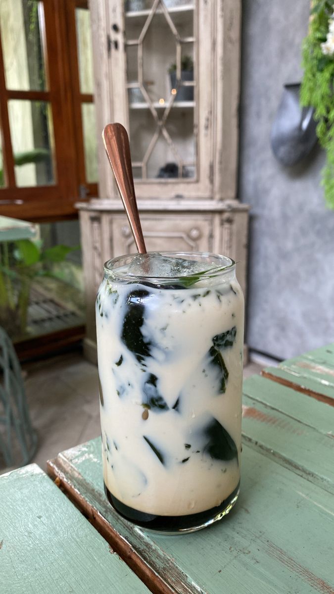 a jar filled with liquid sitting on top of a wooden table next to a cabinet