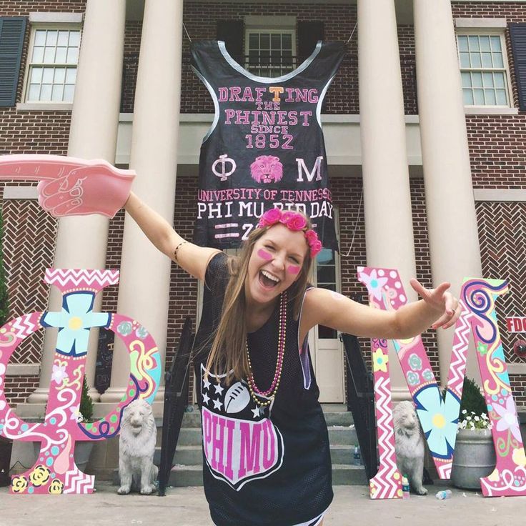 a girl is standing in front of a building with letters and balloons on the ground