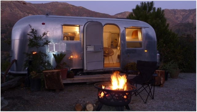 a camper trailer is lit up by the fire pit