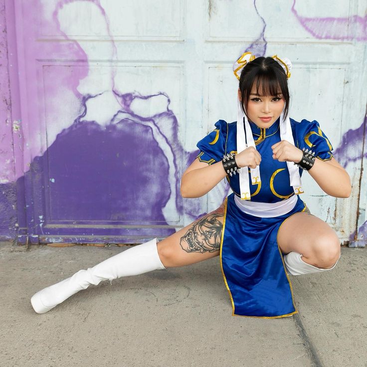 a woman in a blue and white outfit is sitting on the ground with her legs crossed