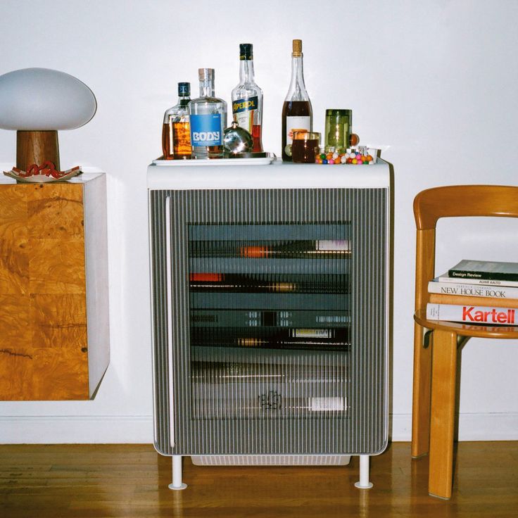 an entertainment center with various liquor bottles on top of it next to a wooden chair