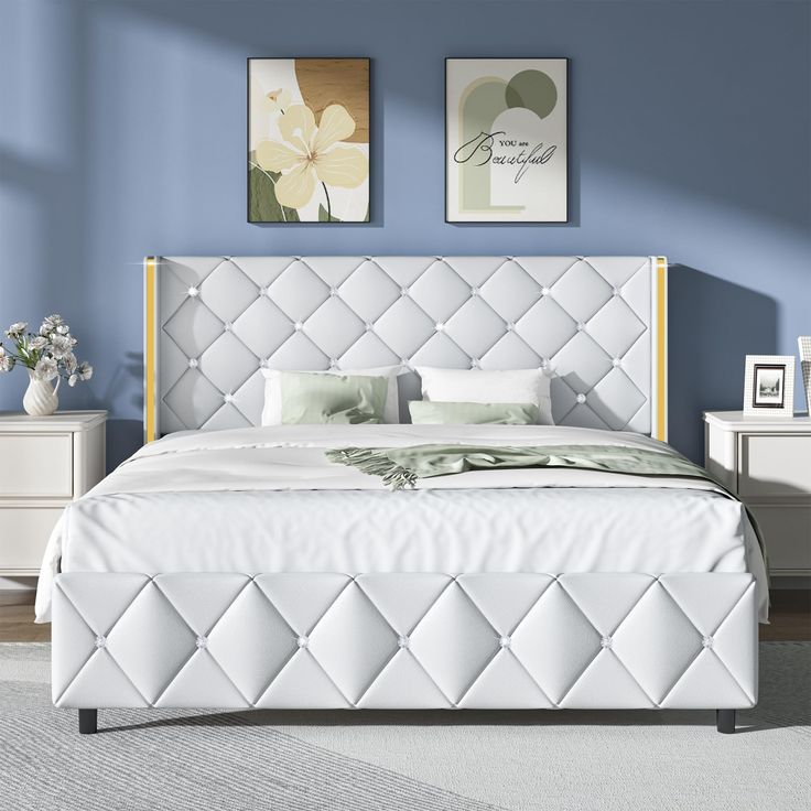 a bedroom with blue walls, white bedding and an upholstered headboard