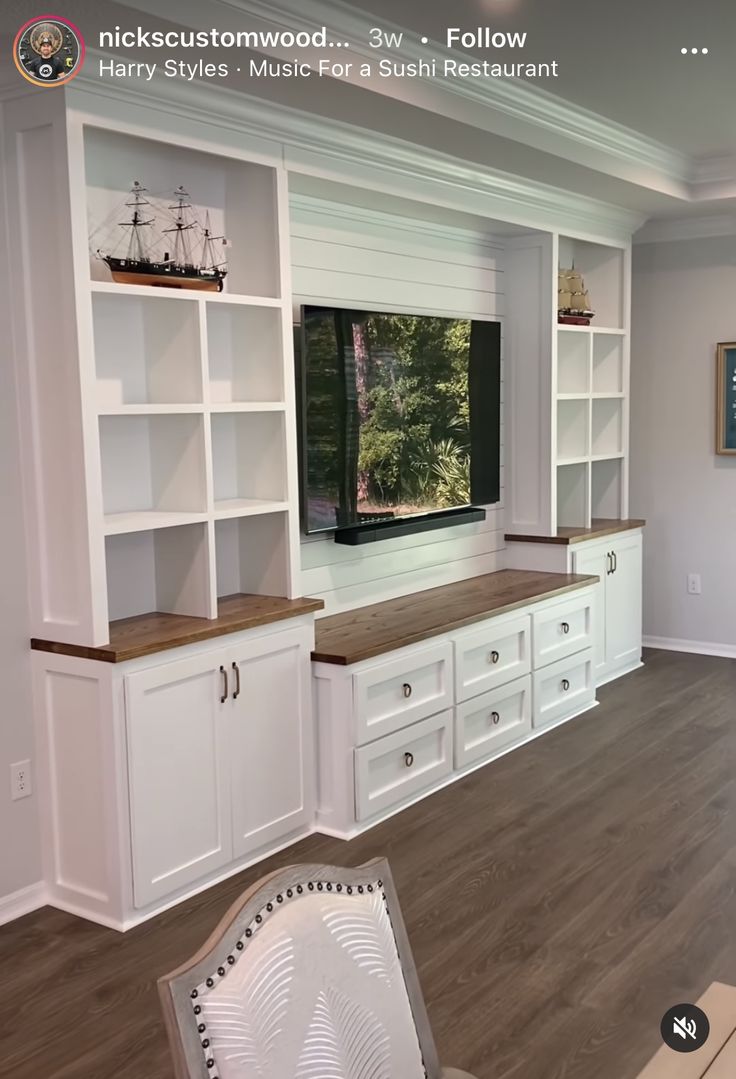 a large entertainment center with white cabinets and wood flooring in a living room area