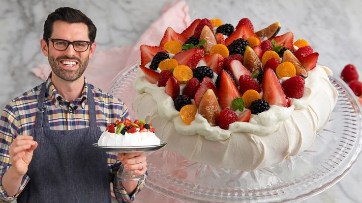 a man holding a cake with fruit on it and a plate full of strawberries