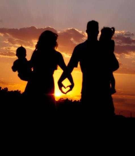 three people holding hands with the sun setting in the background