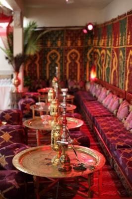 a room filled with lots of purple couches and tables covered in colorful rugs