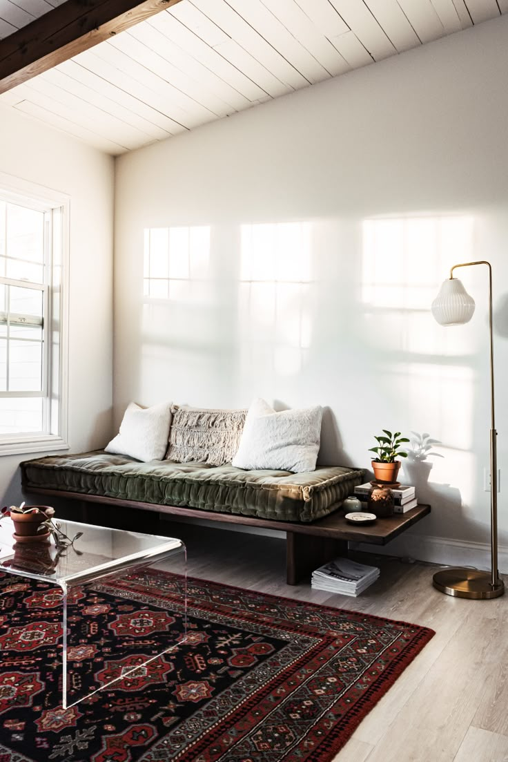 a living room with a couch, rug and lamp on the floor in front of a window