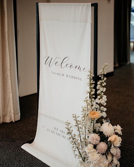 a welcome sign sitting on top of a table next to a vase filled with flowers