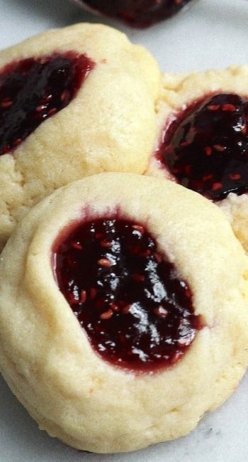 three cookies with jelly filling on them sitting on a white table top next to each other