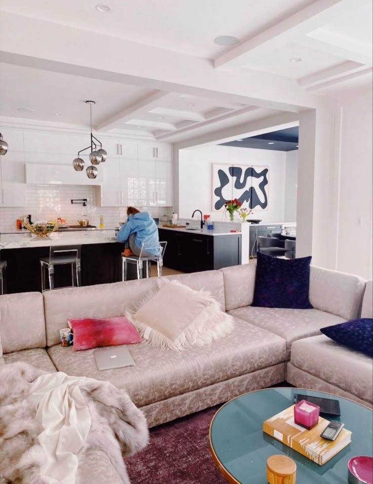 a living room filled with furniture next to a kitchen