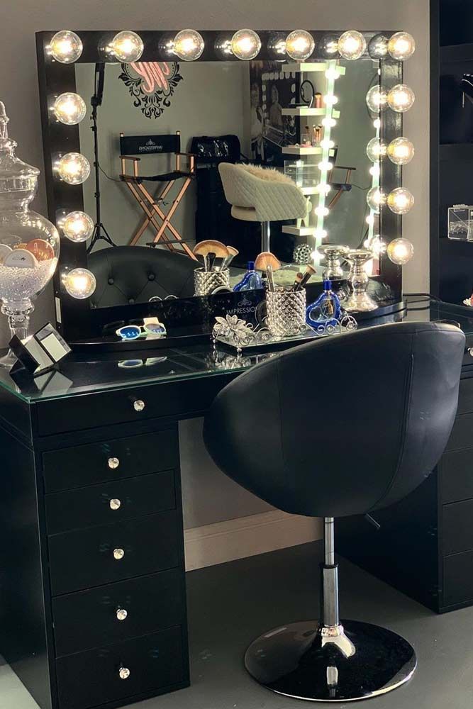 a vanity with lights on it and a chair