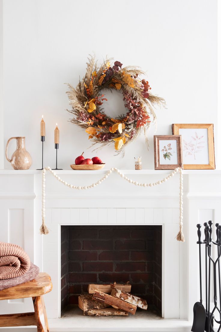 a white fireplace with a wreath on top of it and other decorations around the fire place