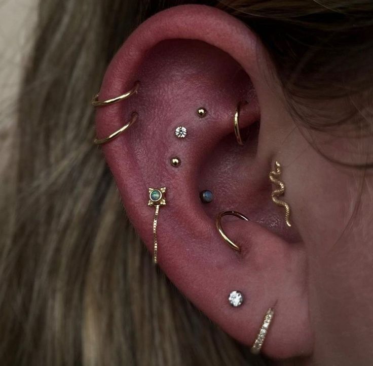 a woman wearing multiple ear piercings on her left ear and the other two are gold