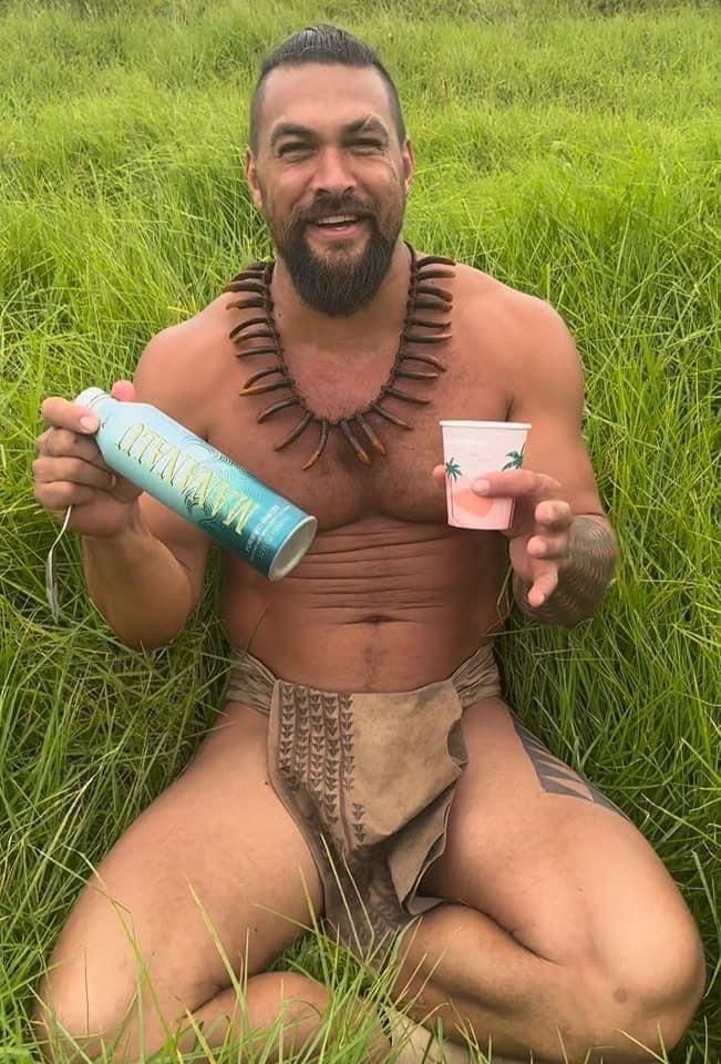 a man sitting in the grass holding two cups