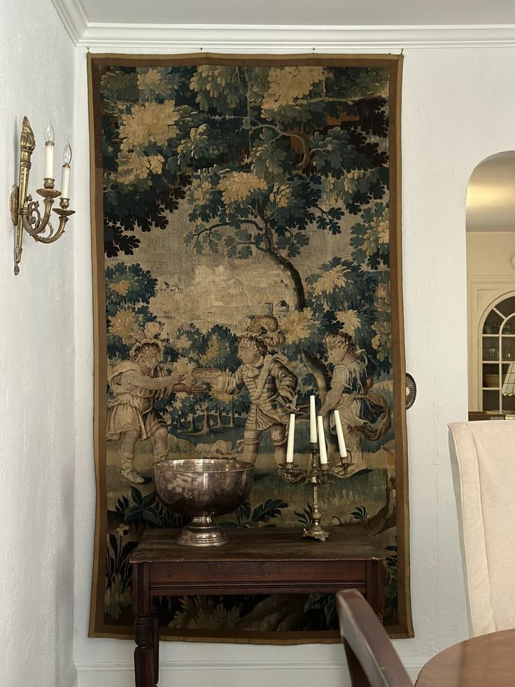 a wall hanging with a tapestry and candles on it next to a table in front of a mirror