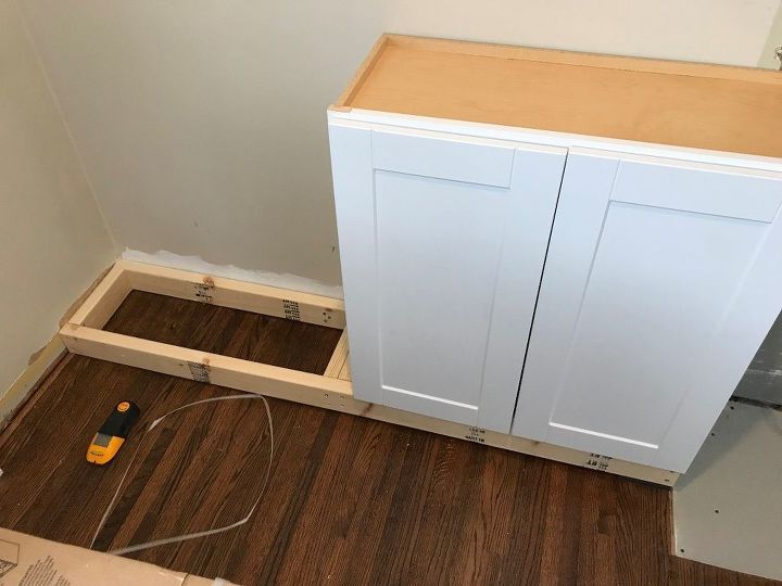 an unfinished kitchen cabinet is being installed in the corner of a room with hard wood flooring