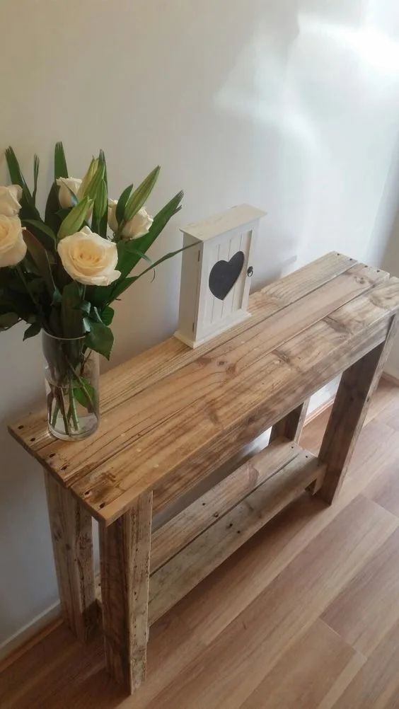 a vase filled with white flowers sitting on top of a wooden table next to a framed photo