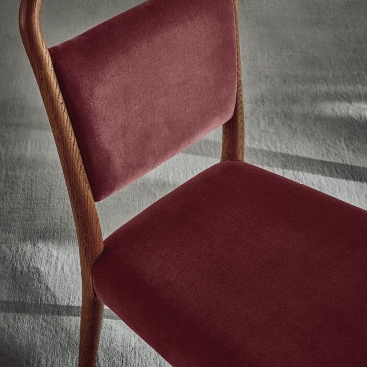 a red chair sitting on top of a carpeted floor next to a wooden frame