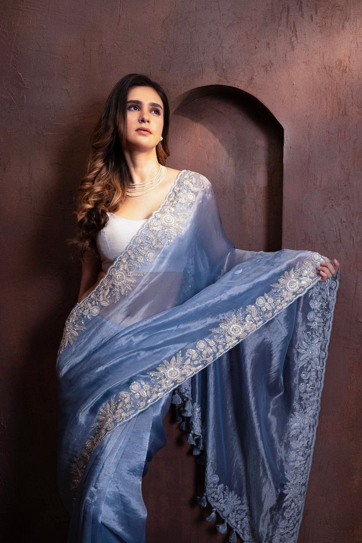 Indulge in the pure luxury of our Hand Embroidered Blue Tissue Organza Saree. Each thread is carefully and meticulously embroidered by hand, creating a one-of-a-kind piece that exudes elegance and sophistication. Elevate your style and make a statement with this exclusive saree. SKU: 0005 Festive Blue Tissue Silk Blouse Piece, Transitional Organza Blouse With Intricate Embroidery, Fitted Blue Tissue Silk Blouse Piece, Elegant Tissue Silk Blouse With Floral Embroidery, Blue Tissue Silk Saree For Reception, Blue Tissue Silk Sets With Traditional Drape, Tissue Silk Blouse Piece With Floral Embroidery, Tissue Silk Embroidered Fabric For Reception, Embroidered Border Dupatta For Reception