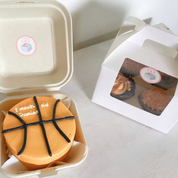 a cupcake in a box with a basketball design on the top and some frosting inside