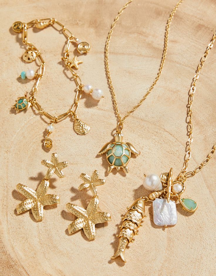 All the wonders of the ocean can be found at your wrist with our Ashore Bracelet. Charms of freshwater & faux pearls, starfish, sand dollar, oyster, sea turtle and more dangle from a 18 KT matte gold plated chain link bracelet. Please note: This design features natural stones and each piece is one-of-a-kind. Colors and patterns may vary slightly from the image shown.