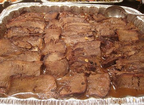 a large metal pan filled with meat on top of a table next to other food