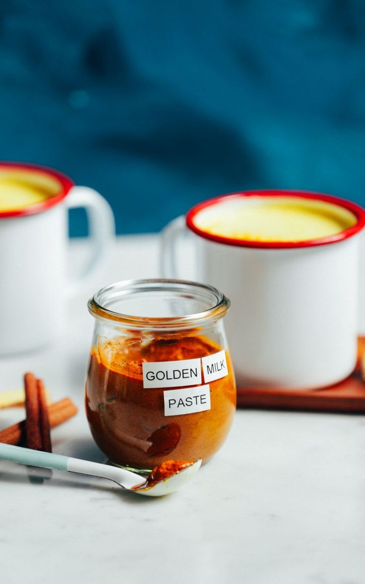 two mugs filled with liquid sitting on top of a table next to cinnamon sticks