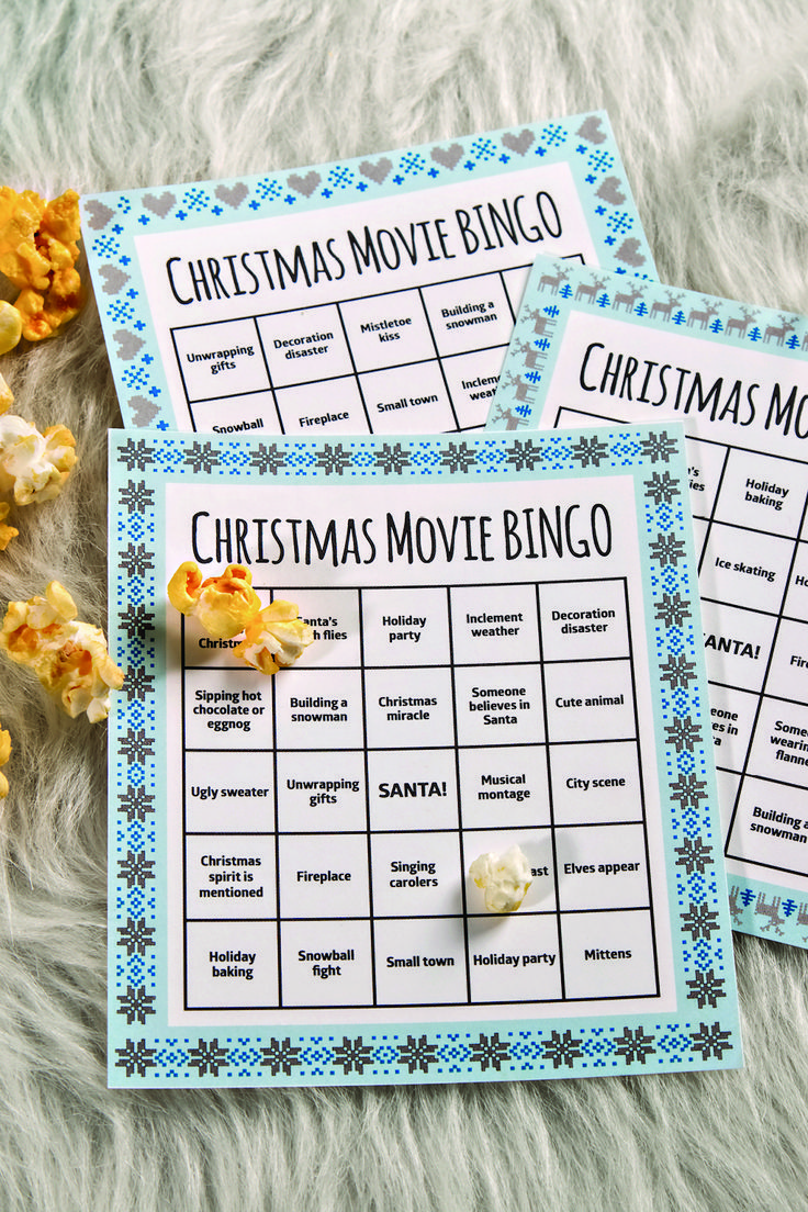 three christmas movie bingo cards with popcorn on the floor and snowflakes around them