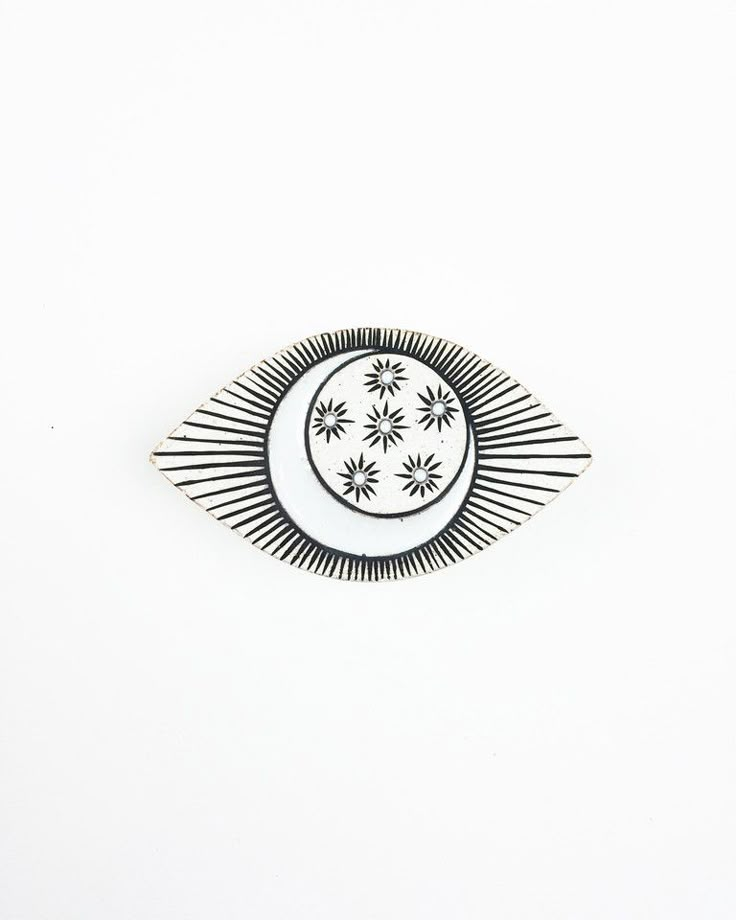 a black and white brooch sitting on top of a white table next to a wall