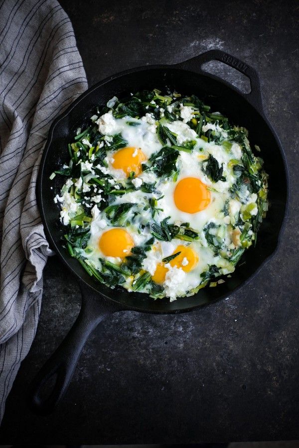 eggs and spinach in a skillet on top of a table with a towel