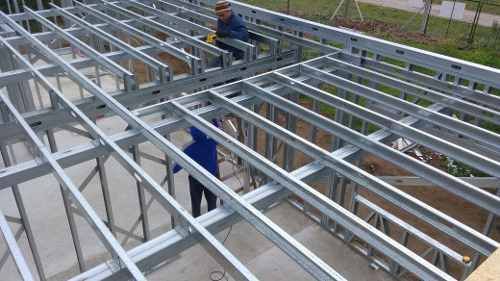 two men are working on the roof of a building that is being built with metal framing