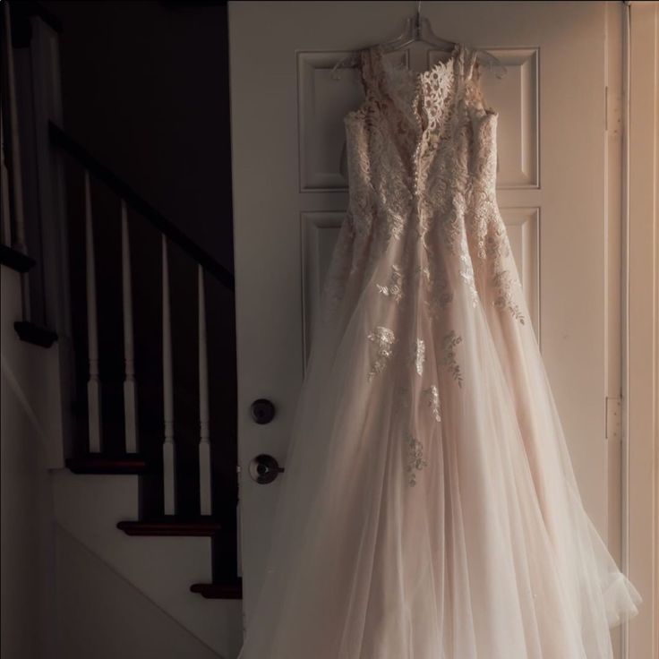 a wedding dress hanging on the door way