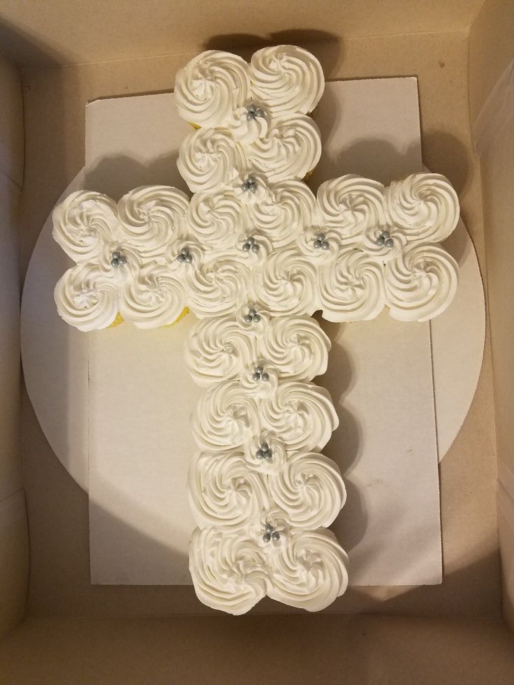 a cake in a box with a cross on it's side and flowers around the edges