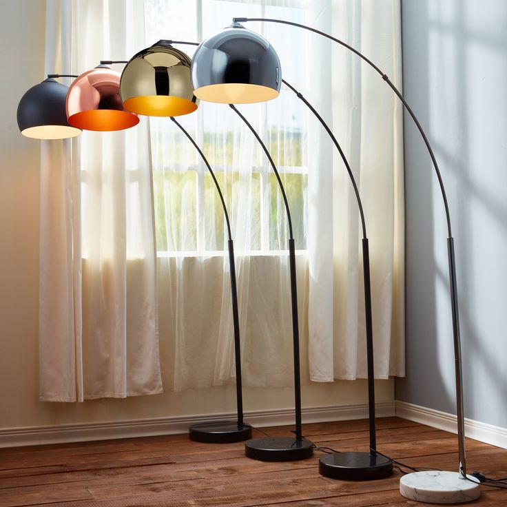 three floor lamps in front of a window