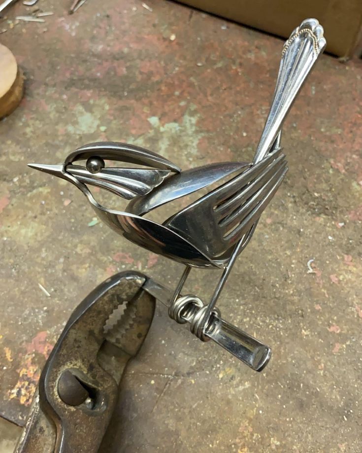 a metal bird sculpture sitting on top of a table next to a pair of scissors